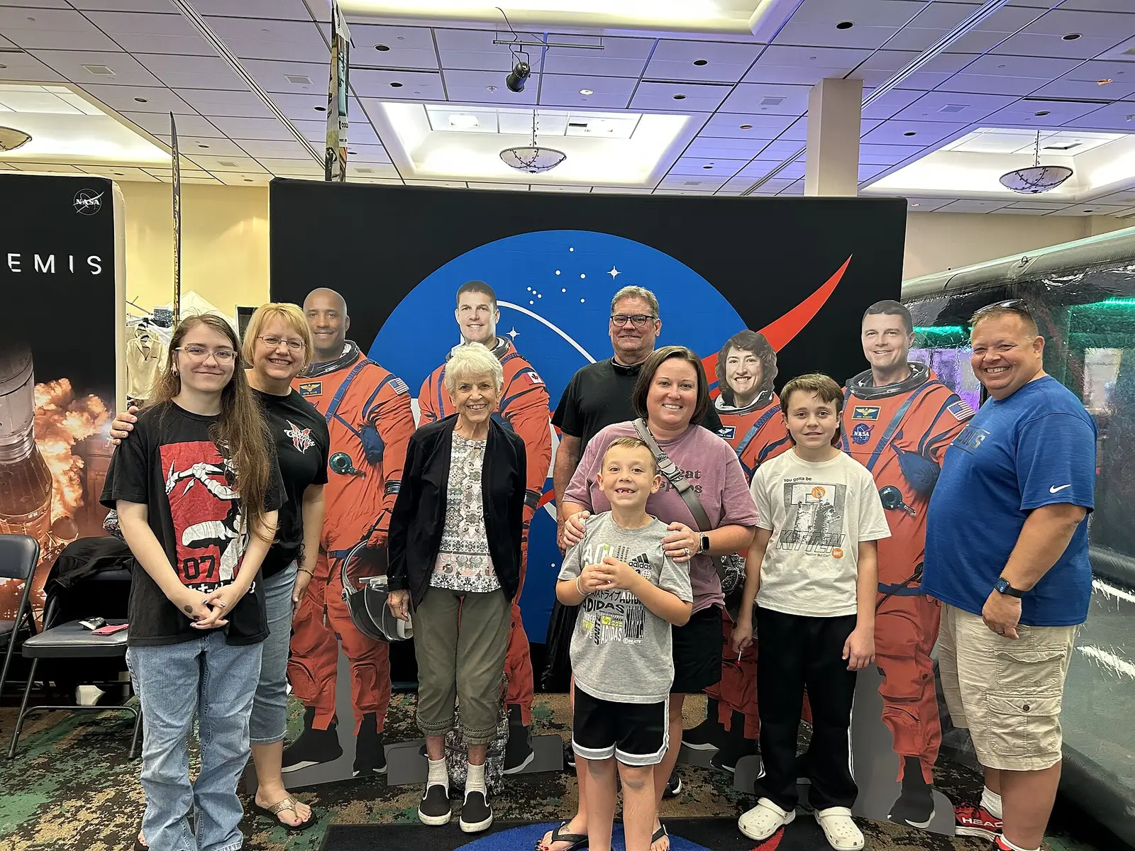 Visitors pose with Artemis II crew cutouts at NASA's Stennis Space Center exhibit during Cruisin' the Coast 2024 at the Mississippi Coast Coliseum in Biloxi.