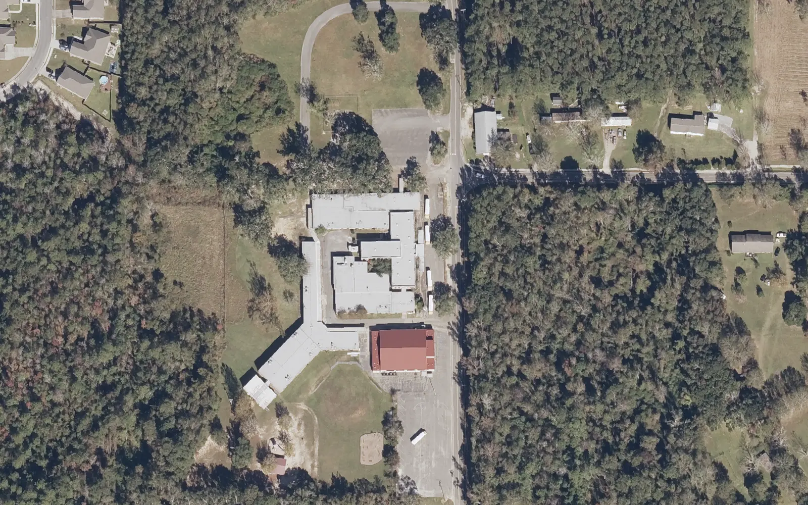 Woolmarket Elementary School and its gym off John Lee Road in Woolmarket, surrounded by pine woods, seen from the air.