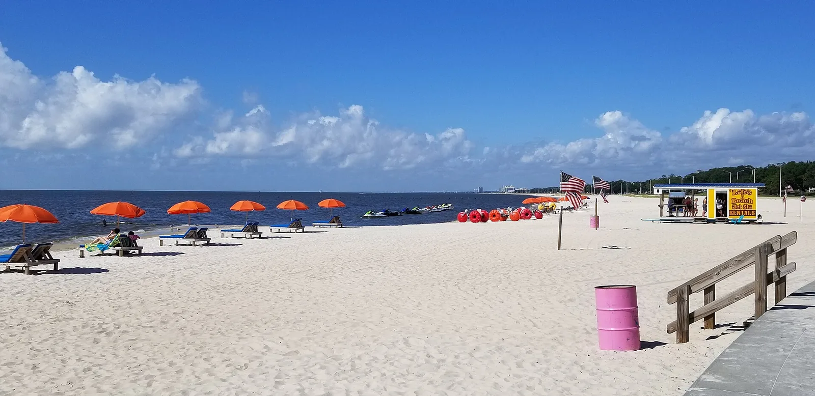 Umbrellas, loungers and a jet ski rental stand on the white sand beach along Beach Boulevard in Biloxi.